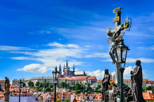 View of Prague castle from Charles Bridge with cross and statues, Czech Republic