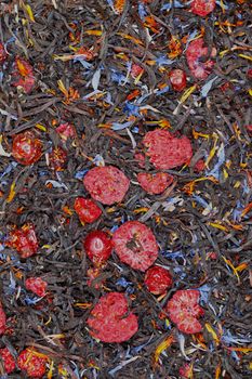 black tea with dried berries and cornflower, textured background