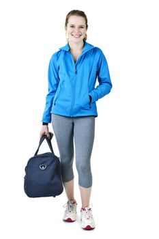 Smiling fit young woman with gym bag standing ready for fitness exercise