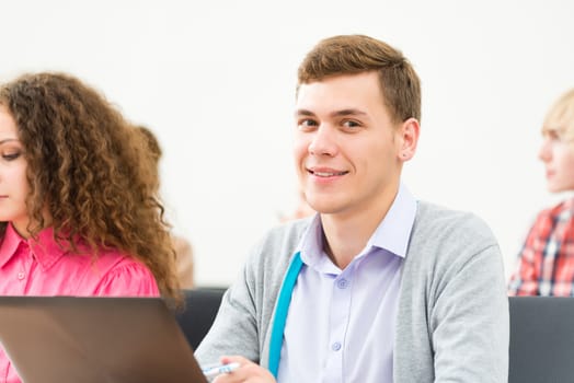 Portrait of a young student in the classroom, working with a laptop