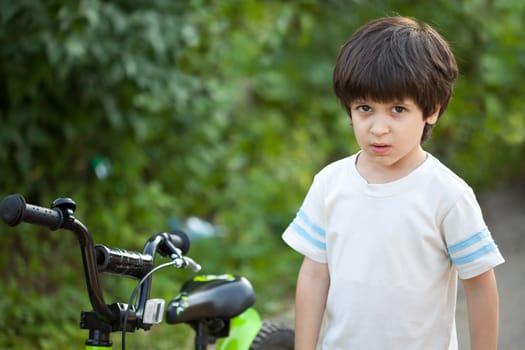serious boy on outdoors with a bicycle
