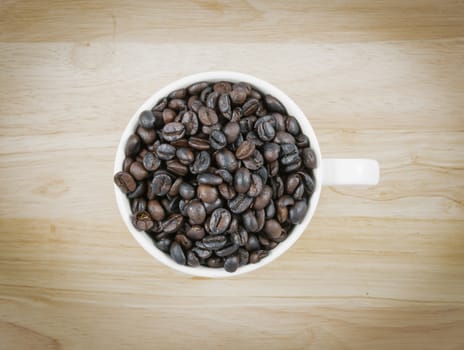 top coffee beans in white cup on brown background