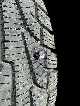 Screw into rubber tire isolated towards black background