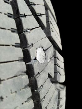 Screw into rubber tire isolated towards black background
