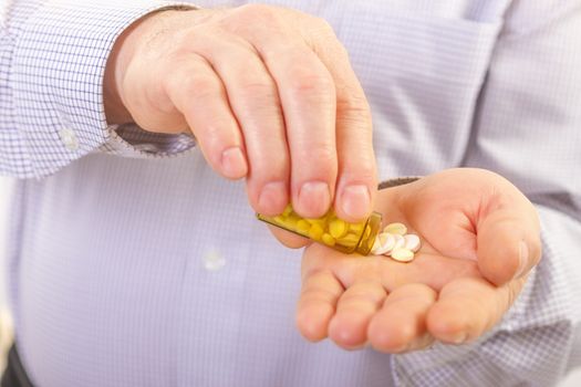 Senior adult man holds medicine capsule in his hand