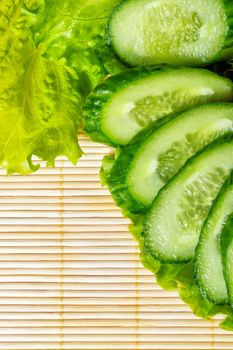 Ripe green cucumber slices and lettuce closeup shot