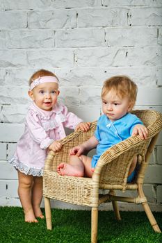 Brother and sister playing in the backyard next to the wicker chair