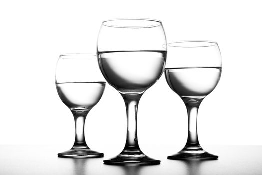 Three simple backlit glases with water on white background