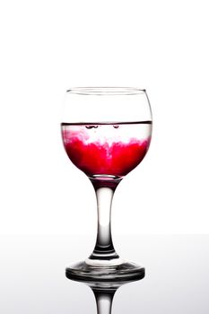 Classy backlit glass of water with red coloring disolwing