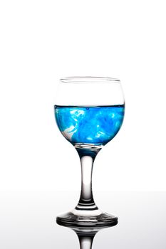 Classy backlit glass of water with blue coloring disolwing