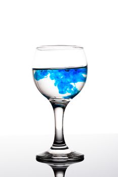 Classy backlit glass of water with blue coloring disolwing