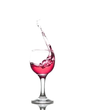 red drink splashes out of glass on white background