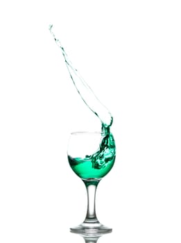 green drink splashes out of glass on white background