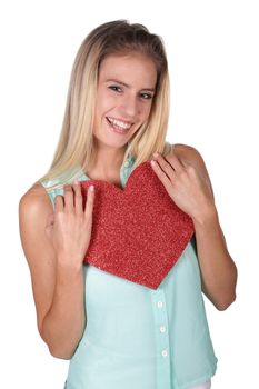 Beautiful young woman holding a big red shiny heart symbol