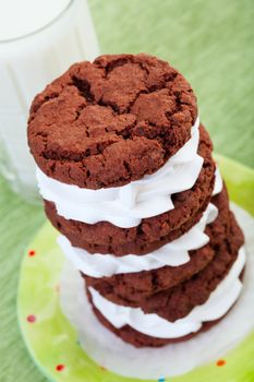 A stack of cream filled chocolate cookies and a tall glass of cold milk.
