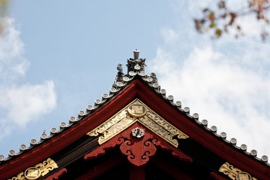 Detail on japanese temple roof against blue sky.