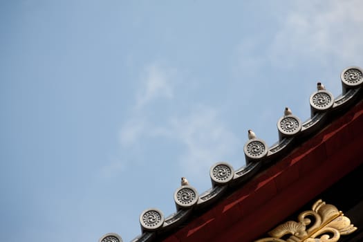 Bird on japanese temple roof against blue sky.