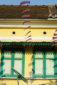 Thailand flag with wooden window on yellow house