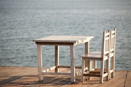 White chairs and table on a balcony with nice view to the sea.