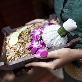 Spa massage setting with thai herbal compress stamps on woman hand