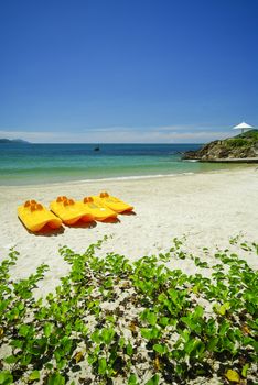 Paddle boats on white sandy beach and emerald sea