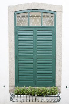 the closed green window on the white wall