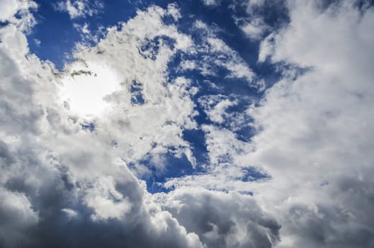 Look up in the sky with sun hiding behind the clouds. 