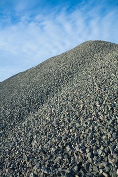 close up view on big pile of gray gravel on background of blue sky