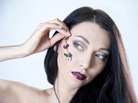 beautiful woman holds the jewels on her face