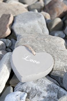 single inscribed grey wooden love heart on a pebble beach in Ireland
