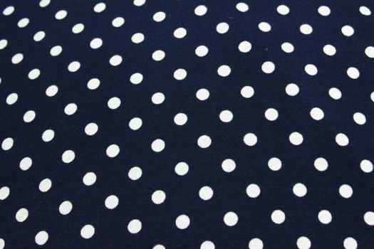 on a dark blue fabric small white polka dots applied in neat rows