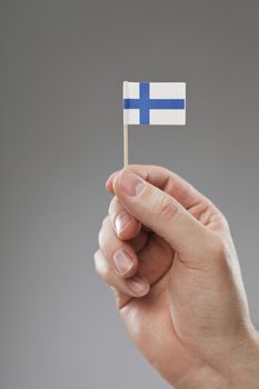 Man holding a tiny Finnish flag in his hand.