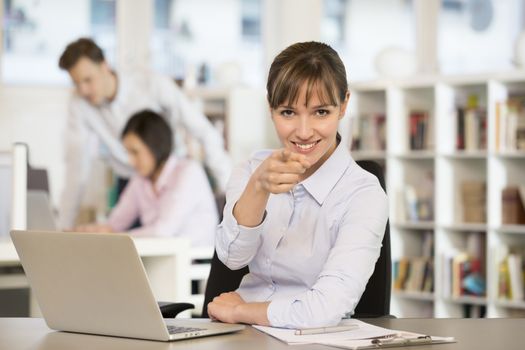 Happy business woman desk smiling point finger computer