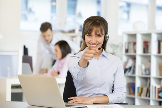Happy business woman desk smiling point finger computer