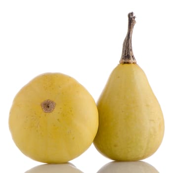 Closeup detail of yellow pumpkins on white reflective background.