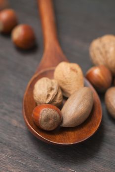 wooden spoon with nuts on a wooden surface