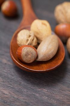 wooden spoon with nuts on a wooden surface