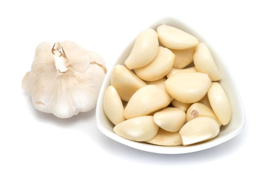 Garlic cloves and bulb in a ceramic bowl on white background