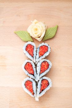 Sushi forming hearts and flower shapes on wooden cutting board