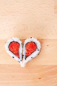 Two pieces of sushi forming the heart shape on wooden cutting board