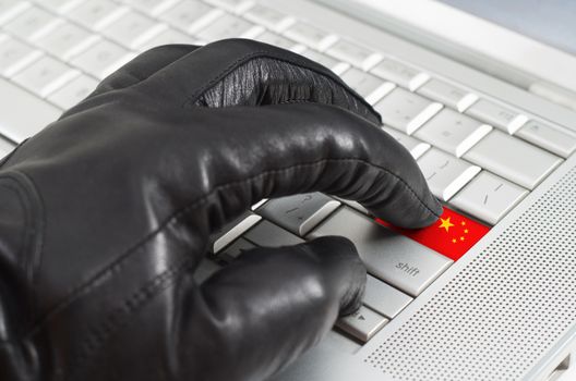 Hacking China concept with hand wearing black leather glove pressing enter key with flag overlaid