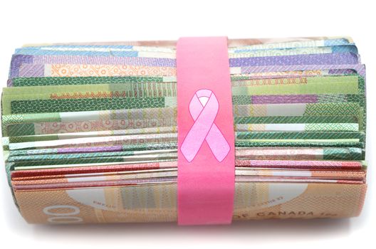 Donation money for cancer treatment with pink ribbon over rubber band