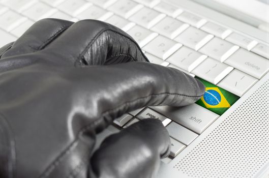 Hacking Brazil concept with hand wearing black leather glove pressing enter key with flag overlaid