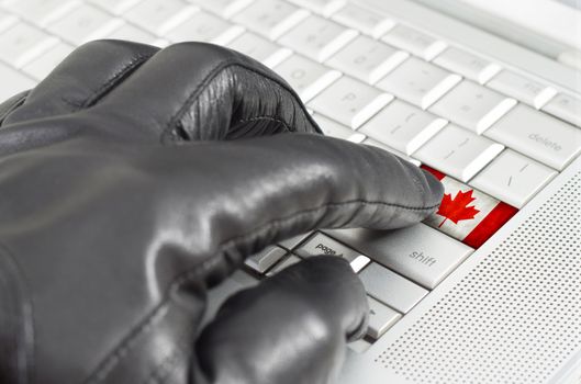 Hacking Canada concept with hand wearing black leather glove pressing enter key with flag overlaid