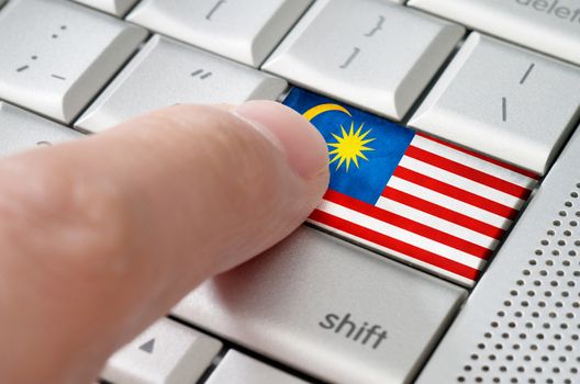 Business concept male finger pressing Malaysia enter key on metallic keyboard