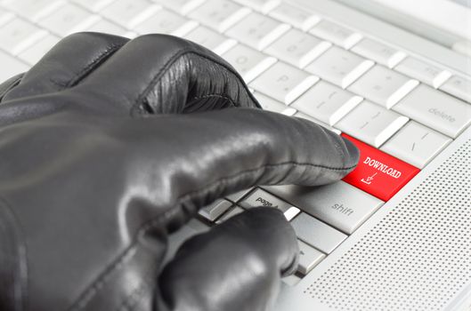 Online illegal download with hand wearing black leather glove pressing enter key