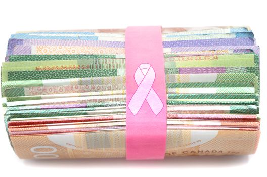 Donation money for cancer treatment with pink ribbon over rubber band