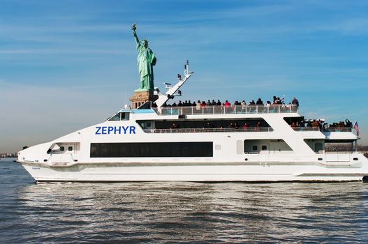 NEW YORK - NOVEMBER 25: Luxury yacht Zephyr filled with tourist  in front of Statue of Liberty on November 25, 2011. Zephyr departs from South Street Seaport for Statue of Liberty Express tours. 