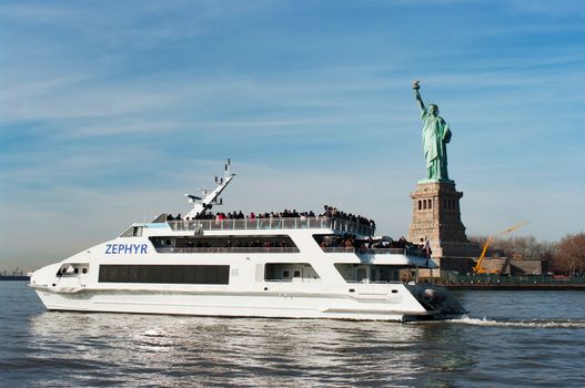 NEW YORK - NOVEMBER 25: Luxury yacht Zephyr filled with tourist  in front of Statue of Liberty on November 25, 2011. Zephyr departs from South Street Seaport for Statue of Liberty Express tours. 