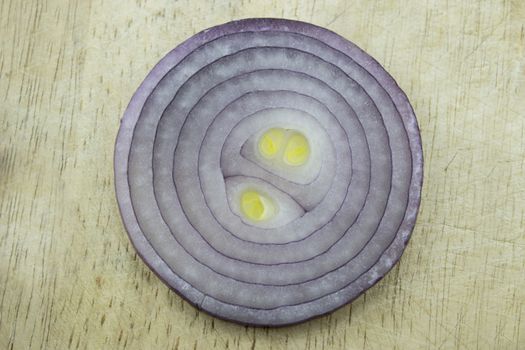 Red sliced onion on wooden kitchen board.